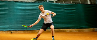 ragazzo con racchetta da tennis sul campo in terra rossa