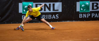 ragazzo con maglietta gialla che gioca a tennis